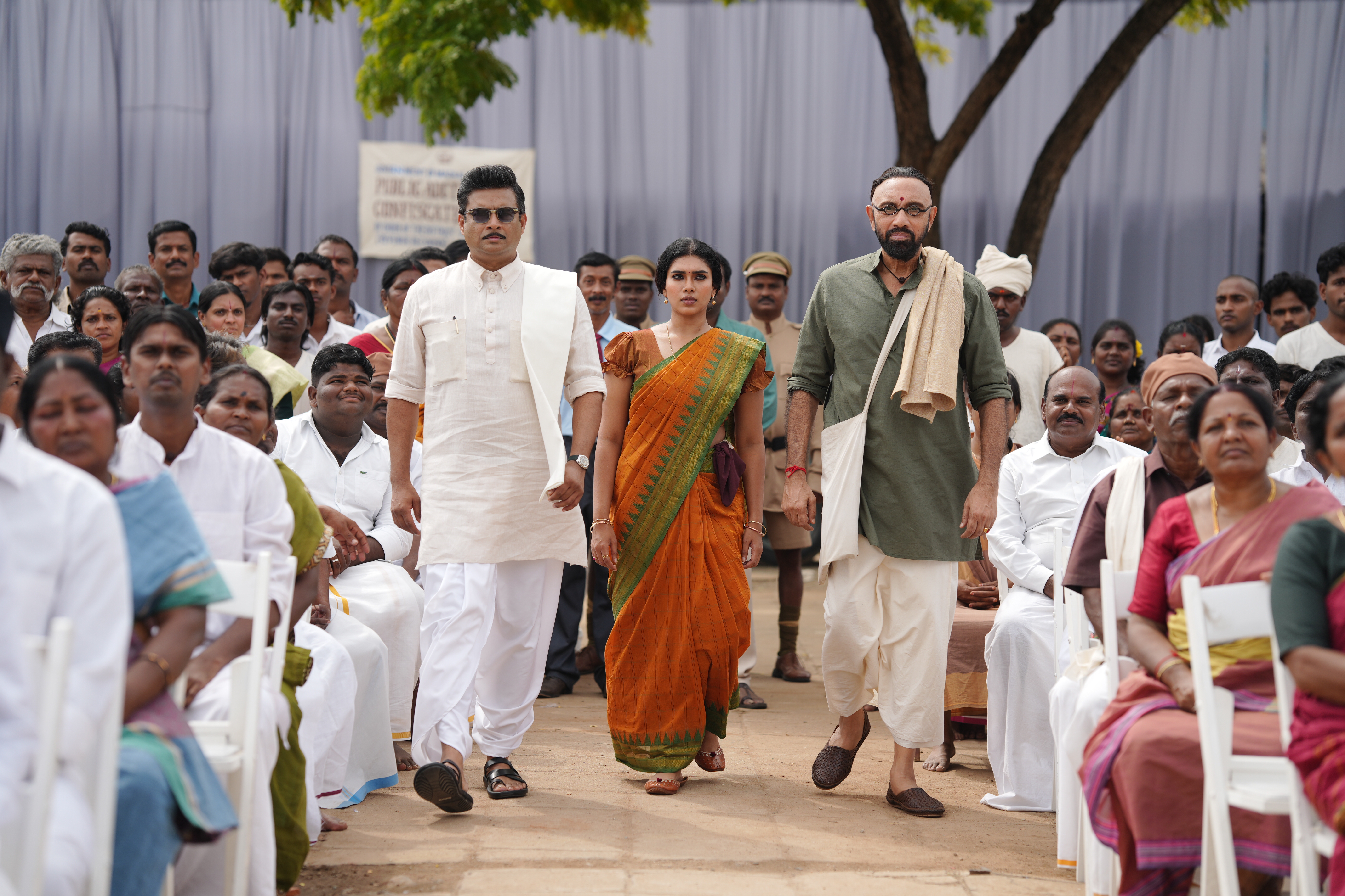 G.D.N. — cast walking through a public gathering scene